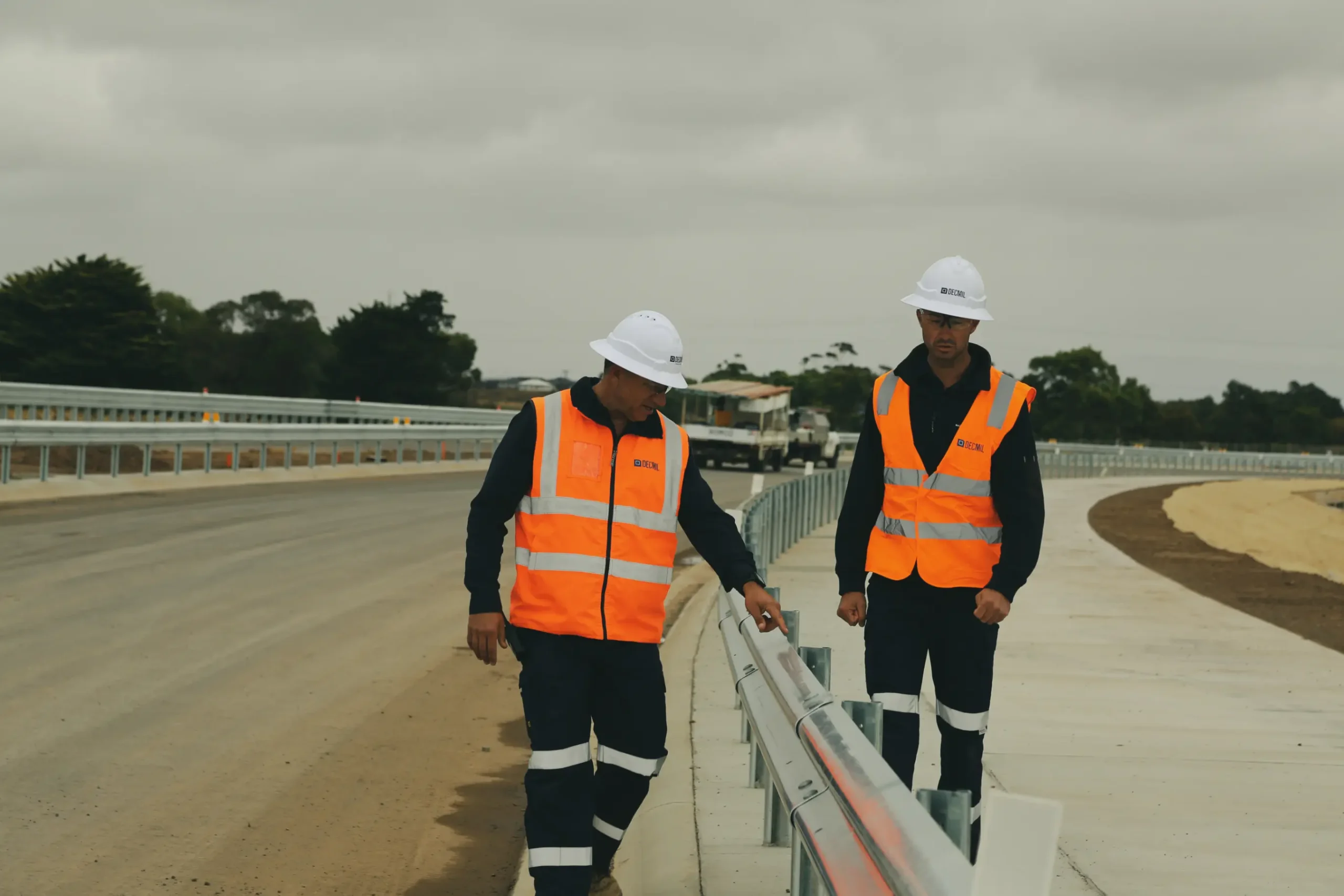 Two Decmil workers inspecting roadside barrier on highway