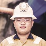 Male miner in yellow hard hat and high-vis shirt smiling