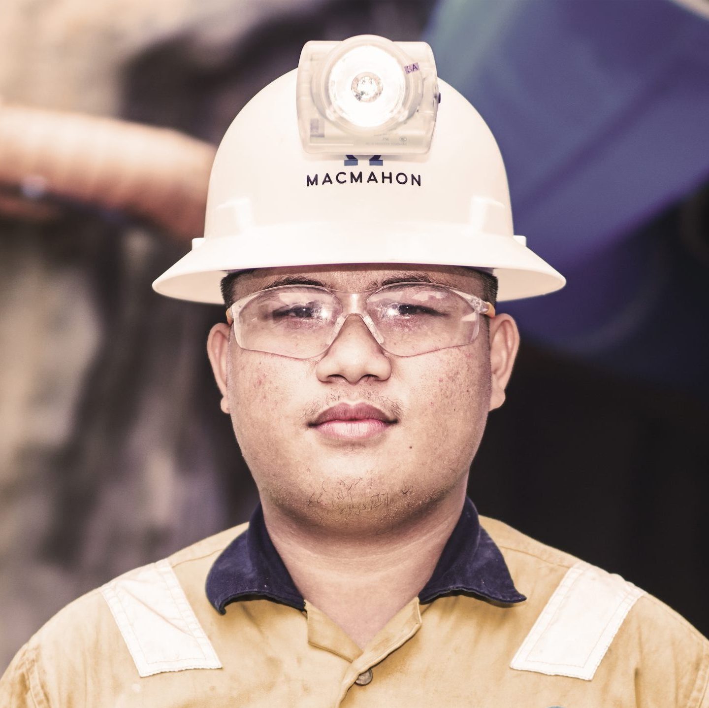 Male miner in yellow hard hat and high-vis shirt smiling