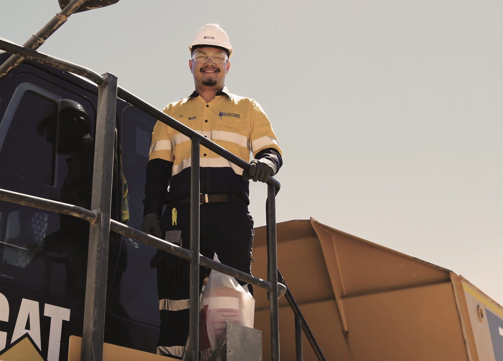 Eli Graham smiling and standing on top of machinery on site