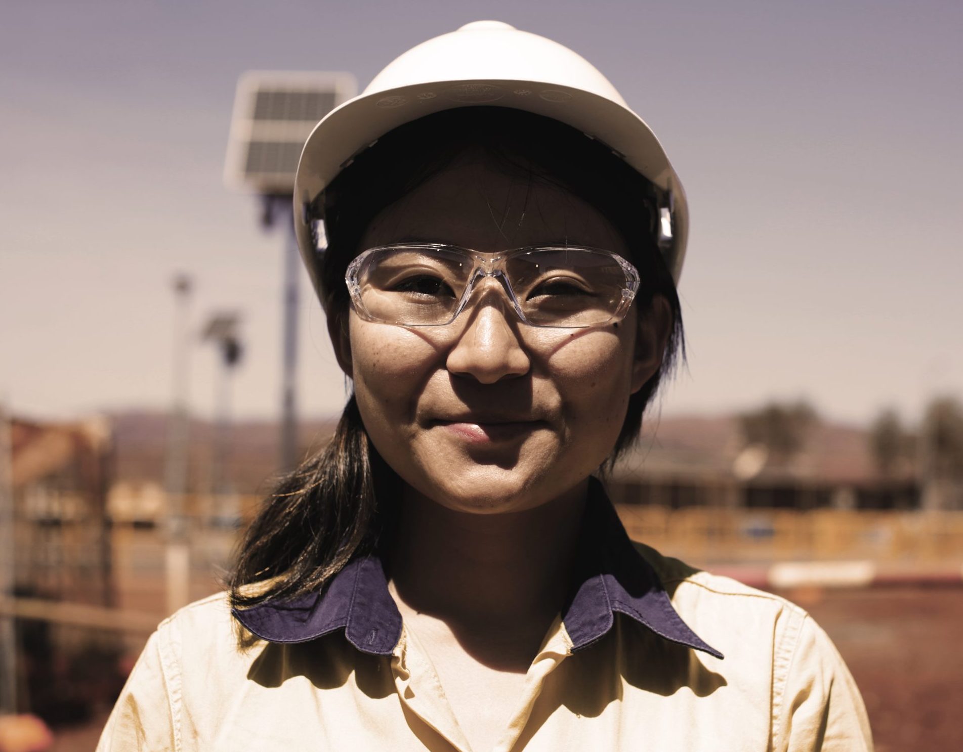 Smiling female Decmil worker in hard hat and safety glasses