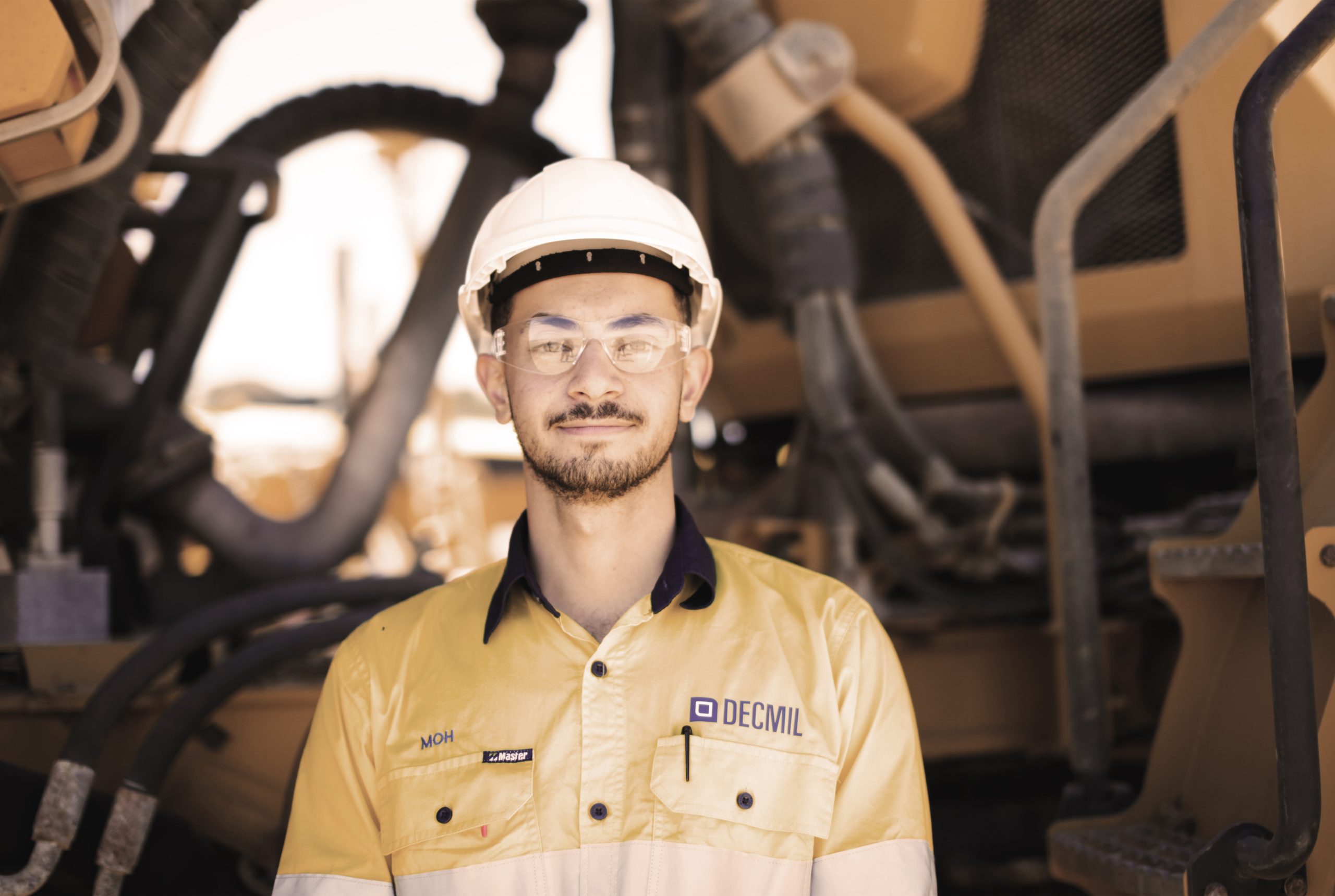 Mohamad Odoh smiling on mine site in front of equipment